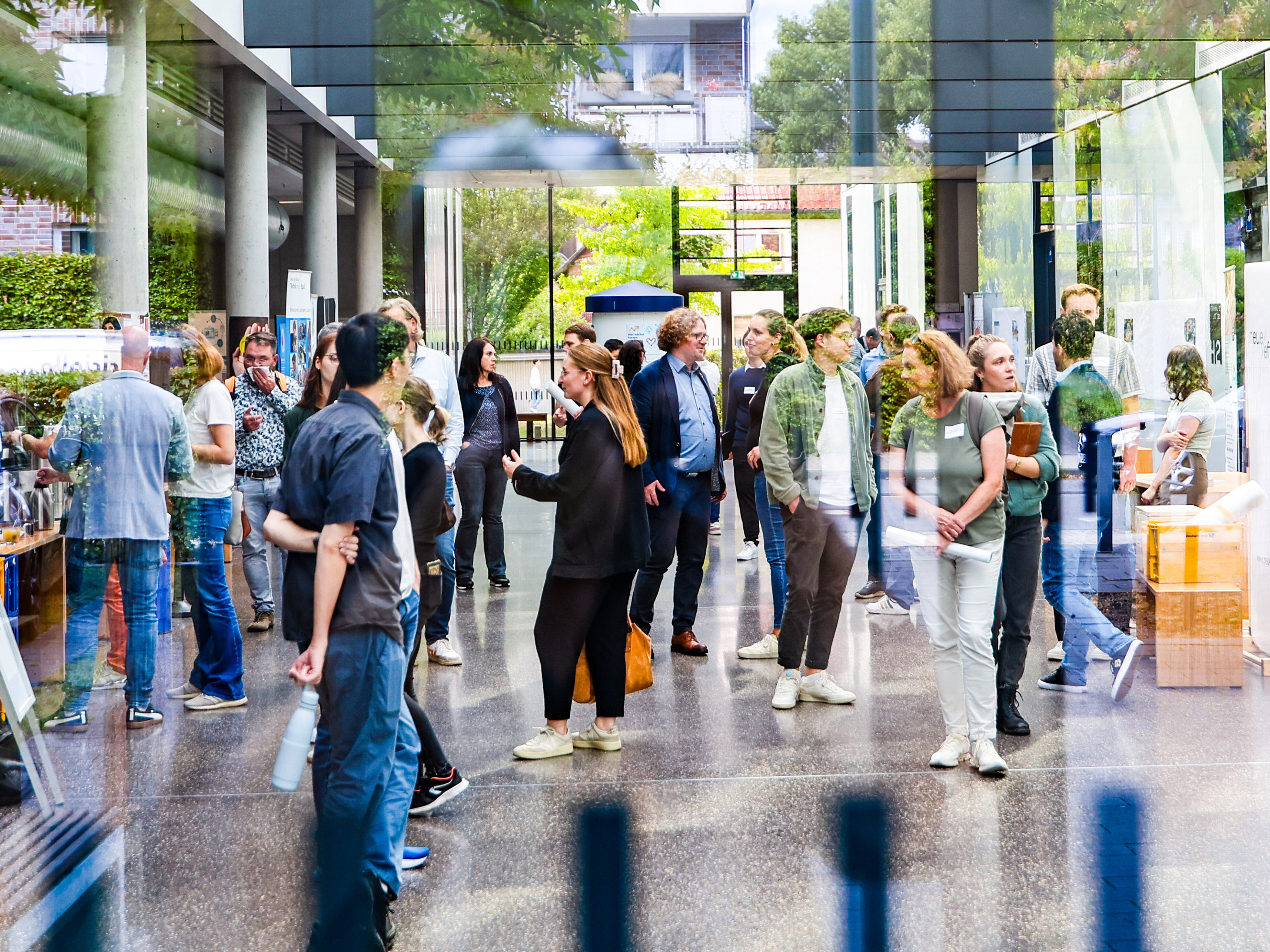 Menschen stehen in der Eingangsgalle des Transferhubs im Ruhrgebiet und betreiben Small Talk.