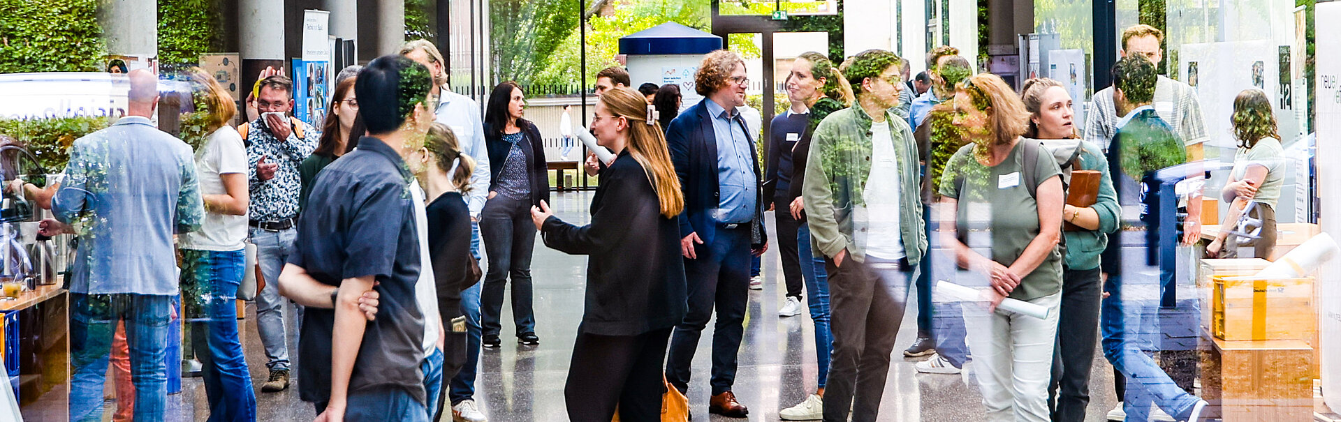 Menschen stehen in der Eingangsgalle des Transferhubs im Ruhrgebiet und betreiben Small Talk.