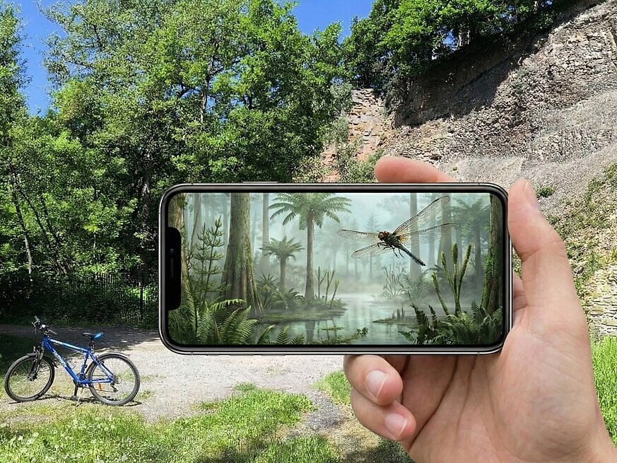 Landschaft mit einem Handy im Vordergrund auf dem eine KI-Visualisierung zu sehen ist