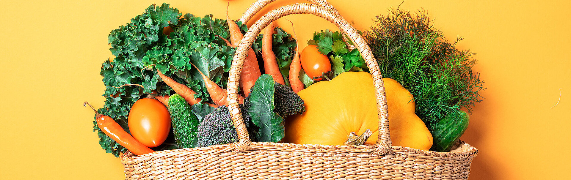 Bild: Strohkorb mit Bio-Gemüse über trendy gelben Hintergrund