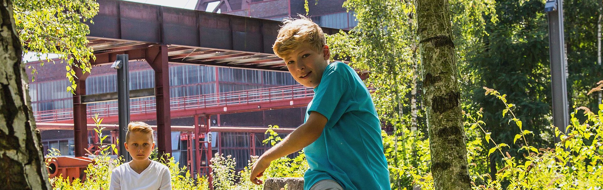 Bild: Zwei fußballspielende Jungs im Hintergrund der Förderturm der Zeche Zollverein